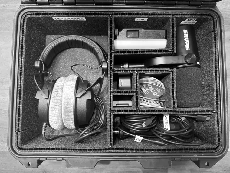 The guest kit open: headphones, a light, a Shure microphone, a webcam and cables in a padded case.