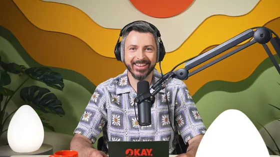 A frame from the video episode: the host at the microphone in front of the set.